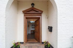 eine offene Holztür in einem weißen Backsteingebäude in der Unterkunft Bedingfield House, nr Debenham in Debenham