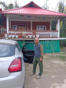 Tsering's Homestay Oyan في باسيغات: رجل يقف بجانب سيارة امام المنزل