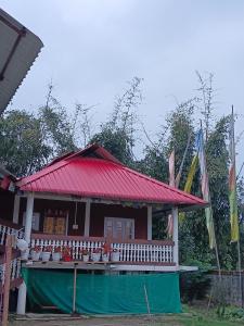 una pequeña casa con techo rojo y bandera en Tsering's Homestay Oyan, en Pāsighāt