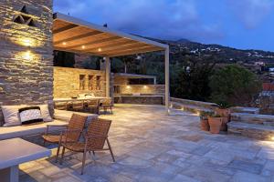 an outdoor patio with chairs and a stone building at Villa Gaia, Beachfront, Plunge Pool & Sunset by Explore Andros in Apróvaton