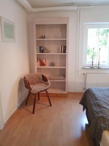 a bedroom with a chair and a book shelf at Ferienwohnung 'dasBRENNERs' in Groß-Umstadt