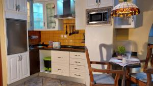 a kitchen with white cabinets and a small table with a table at Apartamentos-Monasterio-de-San-Antonio-Guenstiges-Apartment-zur-Strasse in Icod de los Vinos