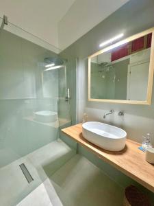 ein Bad mit einem Waschbecken, einem Spiegel und einer Dusche in der Unterkunft Concept Sicily in Syrakus