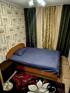 1 dormitorio con 1 cama y una ventana con cortinas en Золотой квадрат, en Astana