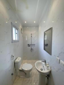 a white bathroom with a toilet and a sink at Cozy Room in Jeddah