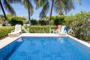 une piscine avec 2 chaises longues et une piscine dans l'établissement Casa a 5 minutos das Piscinas Naturais em Alagoas, à Paripueira