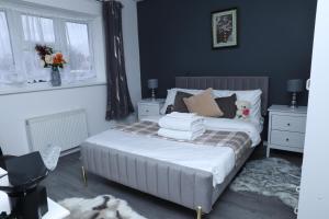 a bedroom with a bed with two night stands and two windows at Beautiful 4-Bed House in Erith in Erith
