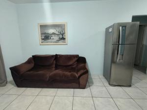a brown couch in a room with a refrigerator at Pousada Golfinhos in Imbé