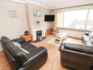 a living room with a leather couch and a fireplace at Murmur y Mor in Goodwick