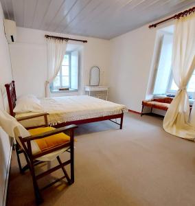 a bedroom with a bed and a chair and two windows at Danaë Port House in Hydra