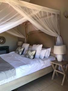 a bedroom with a canopy bed with white pillows at A80@VIPINGO RIDGE in Kilifi