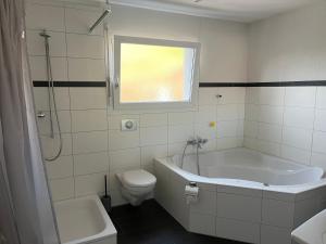 a bathroom with a tub and a toilet and a sink at Schöne Doppelzimmer in Mandach in Böttstein