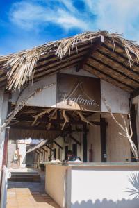a restaurant with a straw roof and a man sitting at a counter at Pousada VIGLAMO JERI in Jericoacoara