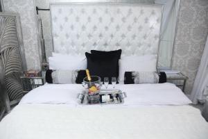 a bedroom with a white bed with a large headboard at Villa Grande Luxury accommodation in Welkom