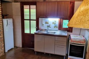 a small kitchen with a sink and a refrigerator at Cabana no Rincão Gaia in Pântano Grande