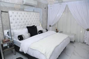 a bedroom with a large white bed with white curtains at Villa Grande Luxury accommodation in Welkom