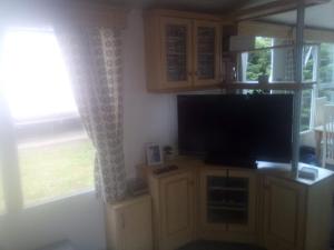 a living room with a flat screen tv and a window at 11 Oaklands in Porchfield