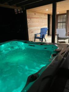 a jacuzzi tub in a house with a chair at Hocking Hills Cottage with beautiful pond in Logan