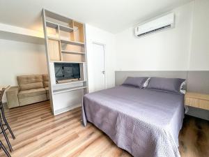 a bedroom with a bed and a tv in a room at Studio Premium Florianópolis in Florianópolis
