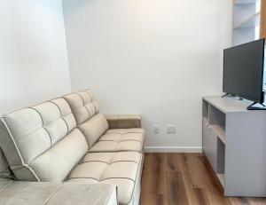 a living room with a couch and a television at Studio Premium Florianópolis in Florianópolis