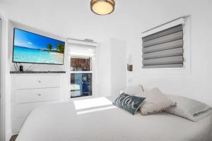 a white bedroom with a bed with a flat screen tv at Tiny Home on Waterfront, Bay Views, Deck, Pool in Jewfish