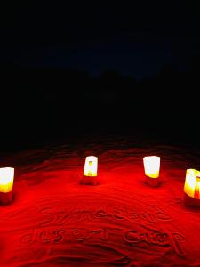 tres velas sentadas sobre una mesa roja en Syndebad desert camp, en Wadi Rum