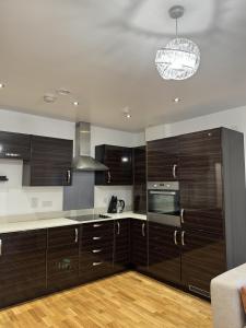 Luxury Apartment in Dartford في دارتفورد: مطبخ مع دواليب خشب داكنة وثريا