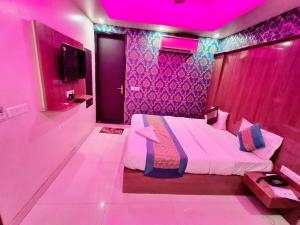 ein rosafarbenes Zimmer mit einem Bett und einer lila Decke in der Unterkunft hotel the paradise inn in Neu-Delhi