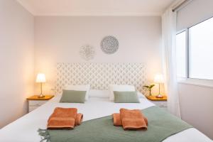 sypialnia z dużym białym łóżkiem i 2 pomarańczowymi ręcznikami w obiekcie Apartamento Renovado "Hogar Las Vistas" w mieście Los Realejos