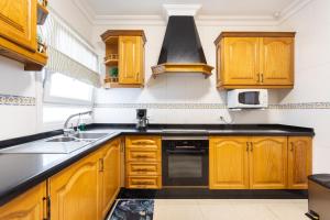 kuchnia z drewnianymi szafkami, zlewem i kuchenką w obiekcie Apartamento Renovado "Hogar Las Vistas" w mieście Los Realejos