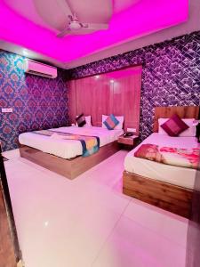 two beds in a room with pink lighting at hotel the paradise inn in New Delhi