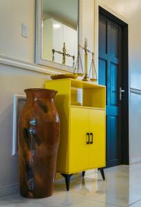 a yellow dresser with a large vase next to a yellow cabinet at Cozy and quirky Wolf Apartment in Paramaribo