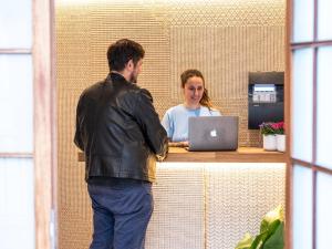 a man and a woman standing at a counter with a laptop at Sweet Lloret Suites in Lloret de Mar
