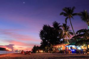 a building on a beach with palm trees at night at Da Kanda Villa Beach Resort in Thong Sala