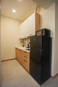 a kitchen with a black refrigerator and wooden cabinets at Grmagele Apartments in Tbilisi City