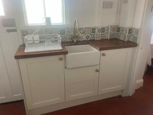 a kitchen with white cabinets and a sink at Long Lane Cottage in Broadwell +29 photos
