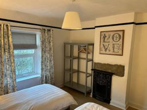 a bedroom with a bed and a fireplace and a window at Long Lane Cottage in Broadwell