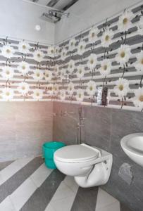 La salle de bains est pourvue de toilettes blanches et de fleurs sur le mur. dans l'établissement Jungle valley Munnar, à Munnar