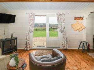 uma sala de estar com uma cadeira de couro e uma porta de vidro deslizante em Westfield Lodge em York