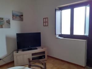 een woonkamer met een flatscreen-tv en een raam bij LA FINESTRA SUL MARE in Trappeto