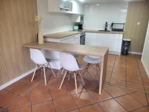 Una cocina con una mesa de madera y sillas blancas. en Apartamento El Olivo, en Vigo 8 fotos más
