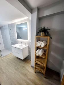 Un baño con lavabo y estante con toallas. en Apartamento El Olivo, en Vigo