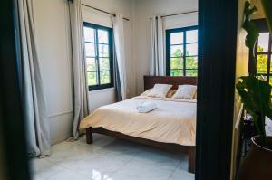 a bedroom with a bed with two windows at Cozy and quirky Wolf Apartment in Paramaribo