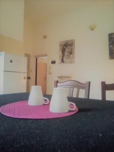 twee mokken op een roze tapijt op een tafel bij Bologna Maison Primaticcio in Bologna