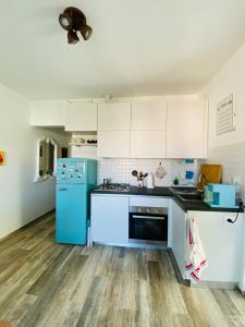 uma cozinha com armários brancos e um frigorífico azul em MALU Bilo CON GIARDINO WIFI E POSTO AUTO IN CENTRO A SIROLO em Sirolo