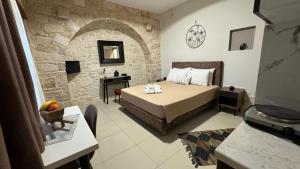 a bedroom with a bed and a stone wall at Aristos Apartments & Suites in Stalos