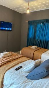 2 Betten in einem Zimmer mit einem TV an der Wand in der Unterkunft Room in El Chalten