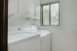 biała pralnia z pralką i oknem w obiekcie Royal Laurentien w mieście Saint-Faustin