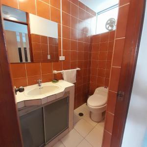 a bathroom with a toilet and a sink and a mirror at Hepico Departamentos Piura in Piura