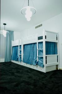 a room with two bunk beds with blue curtains at Curve Hostel JBR in Dubai